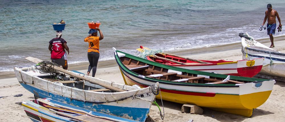 Zwei einheimische kapverdische Frauen transportieren Lebensmittel auf dem Kopf am Strand bei Tarrafa auf der Insel Santiago auf den Kapverden. 