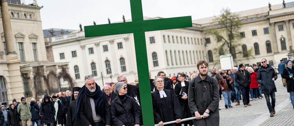 Gläubige tragen bei der Karfreitagsprozession der St. Marienkirche ein grünes Kreuz über den Berliner Bebelplatz.