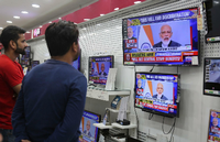 Zwei Inder verfolgen eine Fernsehansprache des indischen Premierministers Narendra Modi in einem Elektronikgeschäft.