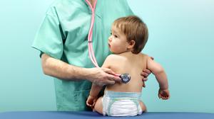 Ein Arzt hört ein Kleinkind mit dem Stethoskop ab.