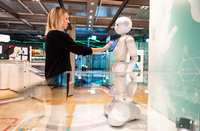 Die Kuratorin Judith Spickermann steht in der Ausstellung: "Künstliche Intelligenz und Robotik" im Heinz Nixdorf MuseumsForum vor einem Serviceroboter Namens Pepper.