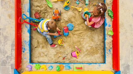 Kinder spielen in einem Sandkasten.