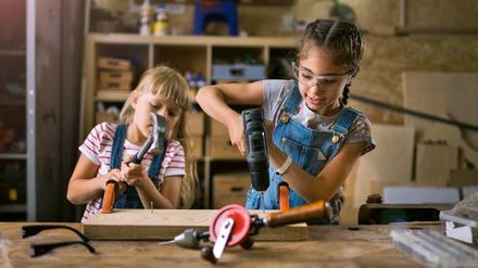 Zwei Mädchen bei Holzarbeiten in einer Werkstatt.