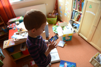 Ein Junge spielt in seinem Kinderzimmer auf einem Smartphone ein Computerspiel.