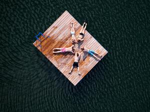 Zwei Mädchen und drei Jungen liegen sternförmig auf einer Holzinsel im Heiseder See bei Sarstedt im Landkreis Hildesheim (Niedersachsen). 