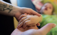 Nicht nur Senioren. Eine Pflegefachkraft hält die Hand eines dreijährigen Mädchens einer Intensivpflege-Wohngruppe für kranke Kinder. -
