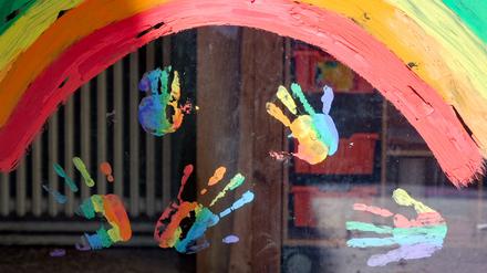 Kinderhände und ein Regenbogen sind an einer Kita zu sehen (Symbolbild).