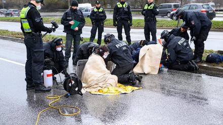 Polizisten arbeiten an den festgeklebten Aktivisten. Klimaaktivisten der Bewegung »Letzte Generation« haben am Samstag die Elbbrücken stadteinwärts blockiert.