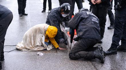 Polizisten lösen den Asphalt um die Hand einer festgeklebten Aktivistin in Hamburg.
