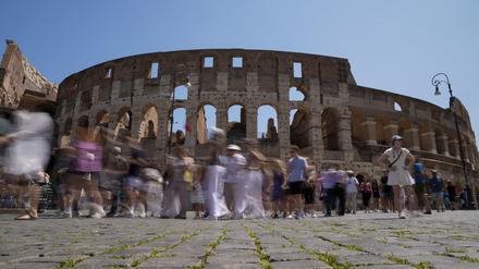 27.06.2023, Italien, Rom: Besucher gehen am Kolosseum in Rom vorbei.