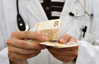 Ein Arzt hält Geldscheine in der Hand.