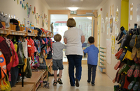 Eine Erzieherin geht im Kindergarten mit zwei Kindern über den Flur der Einrichtung.