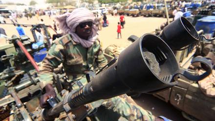Ein Milizionär sitzt neben militärischer Ausrüstung, die angeblich während eines Gefechts im umkämpften Gebiet in Süd-Darfur erbeutet wurde. 