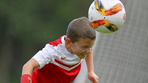 Ein Junge im roten Fußballtrikot spielt einen Kopfball.