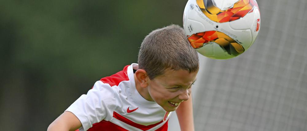 Ein Junge im roten Fußballtrikot spielt einen Kopfball.
