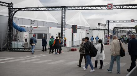 Bewohner und Mitarbeiter gehen im Ankunftszentrum am ehemaligen Flughafen Tegel in Richtung der Leichtbauhallen.