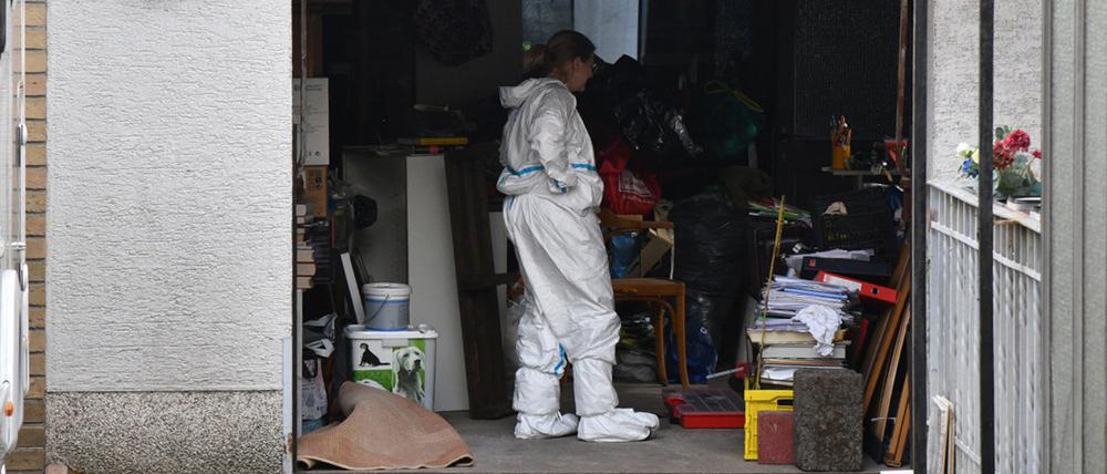 Beamte durchsuchen eine Garage im Umfeld eines Gartens in Homburg im Saarland, in dem eine Leiche gefunden wurde.