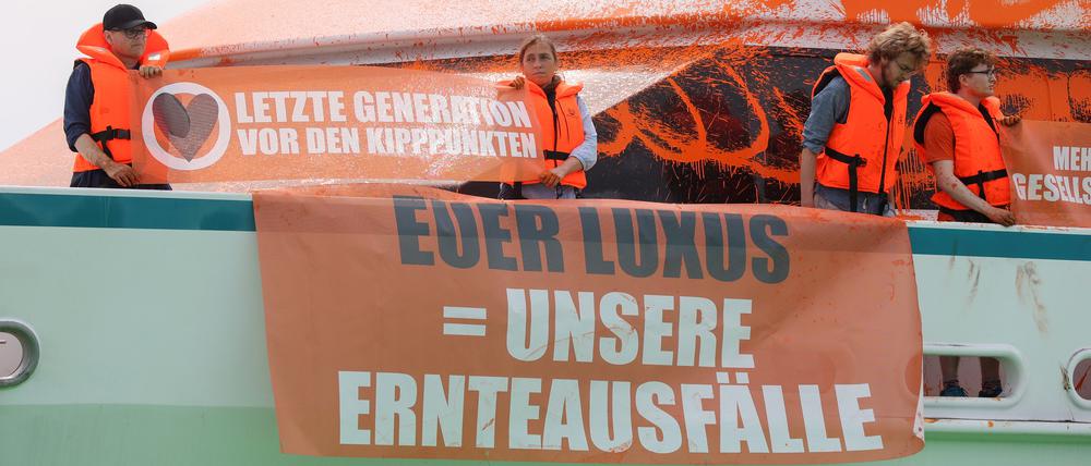 Teilnehmer einer Protestaktion stehen mit Transparenten auf einer Yacht im Hafen von Neustadt. 