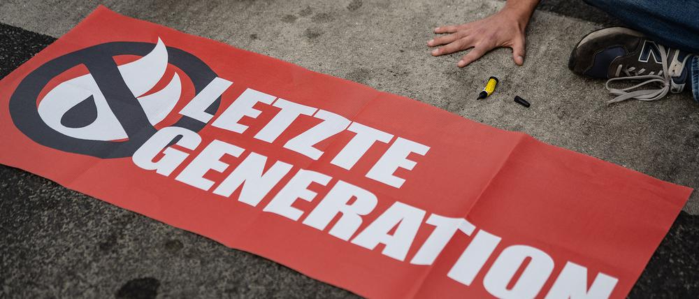 Ein Aktivist der Gruppe „Letzte Generation“, der seine Hand auf der Straße festgeklebt hat, blockiert eine Kreuzung. 