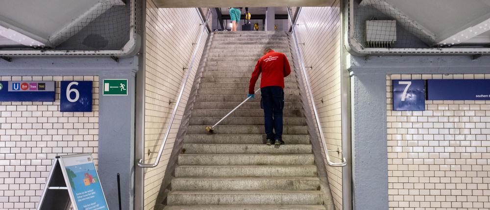 Hart verdientes Geld: Eine Reinigungskraft kehrt in einem Bahnhof einen Treppenaufgang.