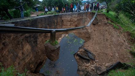 In Malawi gehen Menschen um ein durch den Zyklon verursachtes Loch herum. 