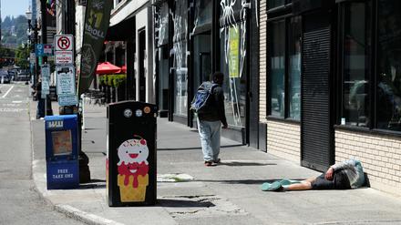 Ein Mann liegt auf dem Fußweg in Downtown Portland. In den USA ziehen Opioide Menschen seit Jahren in den Abgrund. Den Schmerzmitteln wird oft „Tranq“ oft beigemischt.