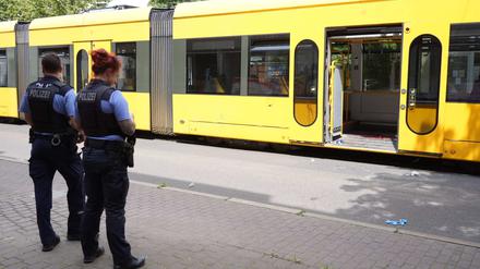 Polizisten stehen vor einer Straßenbahn, in der einem Mann schwere Verletzungen mit einem Messer beigebracht worden waren. 