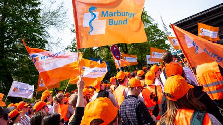 Ärztinnen und Ärzte aus Kliniken in Hamburg nehmen an einem Warnstreik der Ärztegewerkschaft Marburger Bund teil und halten Fahnen hoch.