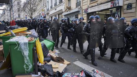 Polizisten marschieren durch die Straßen von Paris, in denen sich der liegen gebliebene Müll türmt. 