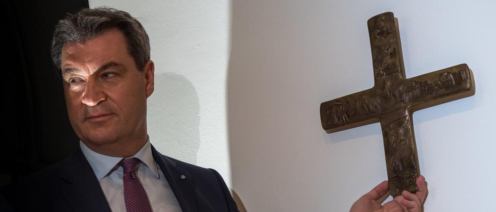 Markus Söder (CSU), bayerischer Ministerpräsident, hängt ein Kreuz im Eingangsbereich der bayerischen Staatskanzlei auf.