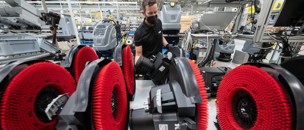 Ein Mitarbeiter eines Reinigungsgeräteherstellers nimmt in der Produktion den Bürstenkopf einer Scheuersaugmaschine von einer Ablage. Die deutschen Maschinenbauer beschäftigen mehr als eine Million Mitarbeitende. 