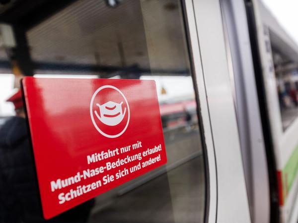 Ein Schild mit der Aufschrift „Mitfahrt nur mit Mund-Nase-Bedeckung erlaubt! Schützen Sie sich und andere!“ klebt an der Zugtür eines ICE der Deutschen Bahn.