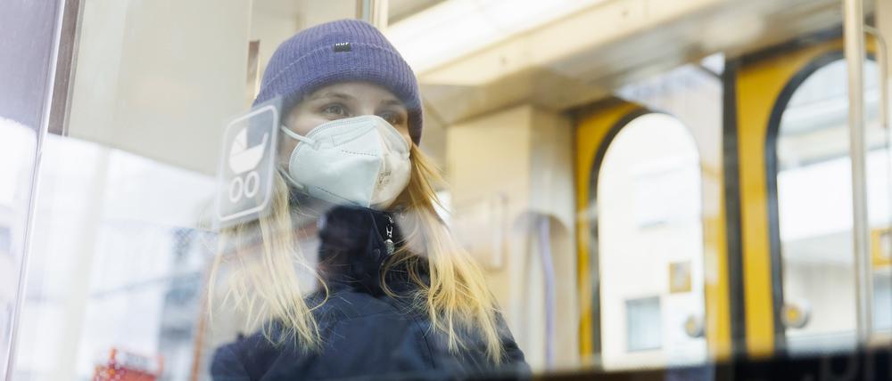 Eine Frau mit Mund-Nasenschutz sitzt in einer Straßenbahn. Sachsen-Anhalt hat als erstes Bundesland die Maskenpflicht aufgehoben. 