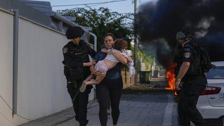 Israelische Polizei evakuiert eine Frau und ein Kind von einem Ort, der von einer aus dem Gazastreifen abgefeuerten Rakete getroffen wurde. An anderen Orten wurden auch Kinder und Babys getötet.