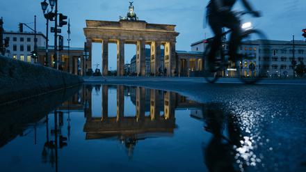 Blick auf das Brandenburger Tor. Berlins Wahrzeichen spiegelt sich bei Nacht in einer Pfütze.
