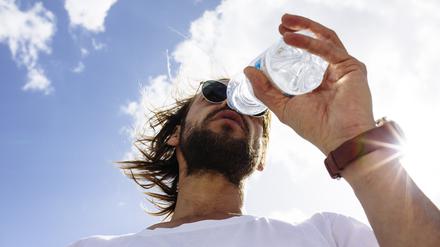 Low Angle View Of Man Wearing Sunglasses And Drinking Water Against Sky