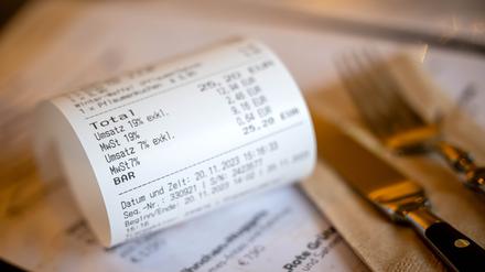 Eine Rechnung mit Umsatzsteuer und Mehrwertsteuer liegt auf der Speisekarte eines Restaurants. Ab 1. Januar gilt auf Speisen in der Gastronomie wieder der volle Mehrwertsteuersatz von 19 Prozent. Nicht alle Restaurants wollen das sofort komplett weitergeben. 