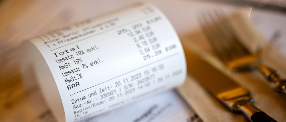 Eine Rechnung mit Umsatzsteuer und Mehrwertsteuer liegt auf der Speisekarte eines Restaurants. Ab 1. Januar gilt auf Speisen in der Gastronomie wieder der volle Mehrwertsteuersatz von 19 Prozent. Nicht alle Restaurants wollen das sofort komplett weitergeben. 