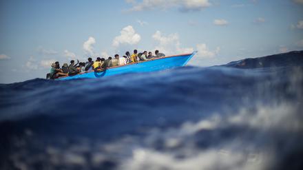 Migranten sitzen in einem Holzboot südlich der italienischen Insel Lampedusa auf dem Mittelmeer (Archivbild).