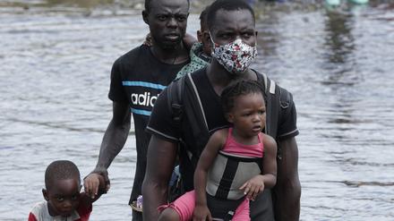 Panama, Panama-Stadt: Migranten aus Haiti überqueren am 10. Februar 2021 den Fluss Tuquesa nach einer Reise zu Fuß durch den Dschungel nach Bajo Chiquito, in der Provinz Darien.