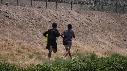 Zwei junge Migranten laufen an der Grenze entlang in der Hoffnung, über den Stacheldrahtzaun in die USA gelangen zu können.