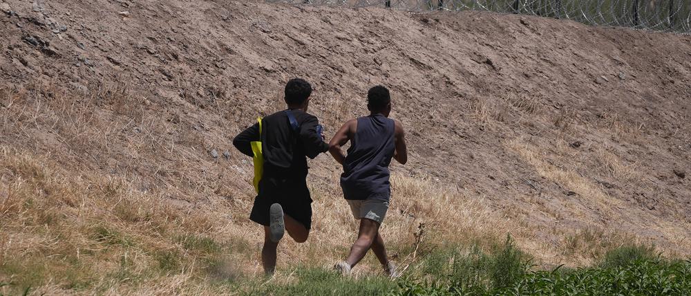 Zwei junge Migranten laufen an der Grenze entlang in der Hoffnung, über den Stacheldrahtzaun in die USA gelangen zu können.