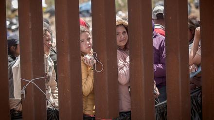 Frauen stehen hinter der Grenzmauer zwischen Mexiko und USA und hoffen darauf, in die USA einreisen zu können.