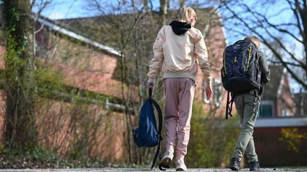 Eine Schülerin geht in einer Jogginghose auf dem Schulhof einer Schule.