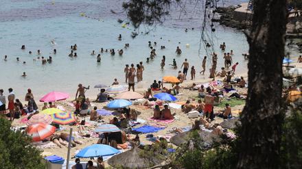 Menschen schwimmen und sonnen sich am Strand von Illetes auf Mallorca.