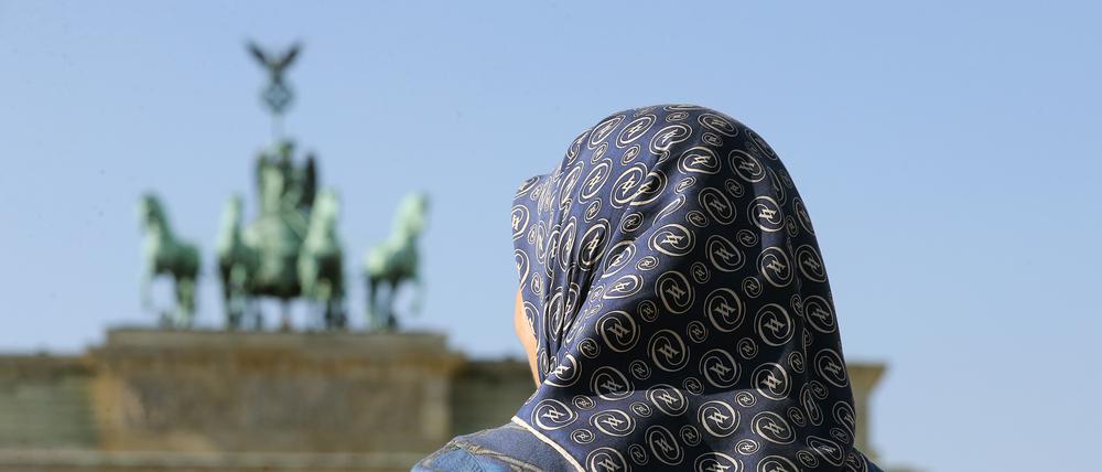 Eine muslimische Frau mit Kopftuch vor dem Brandenburger Tor in Berlin. 
