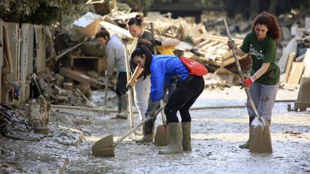 22.05.2023, Italien, Faenza: Freiwillige säubern eine Straße nach schweren Überschwemmungen mit Schaufeln. 