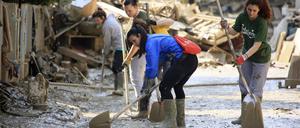 22.05.2023, Italien, Faenza: Freiwillige säubern eine Straße nach schweren Überschwemmungen mit Schaufeln. 