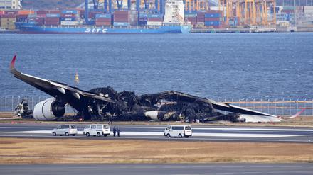 Einsatzkräfte untersuchen das Wrack der Japan Airlines-Maschine auf dem Flughafen Haneda.