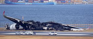 Einsatzkräfte untersuchen das Wrack der Japan Airlines-Maschine auf dem Flughafen Haneda.